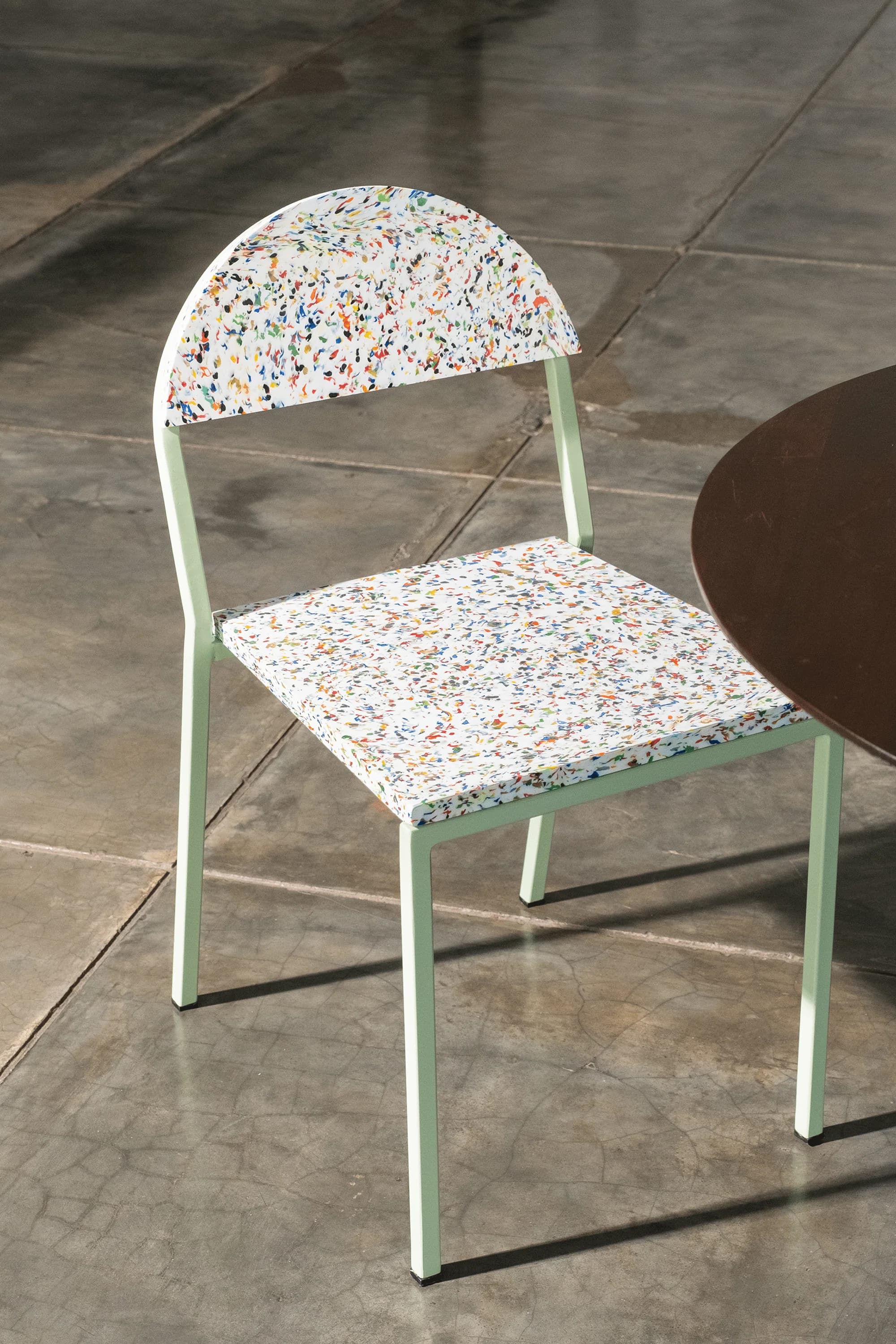 Two faded blue plastic chairs on a paved street